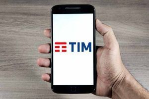 mano tiene in mano smartphone con logo TIM sullo schermo