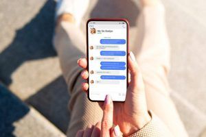 persona tiene in mano smartphone con aperta app di messaggistica istantanea