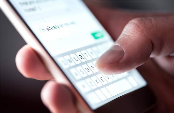 persona tiene in mano smartphone e digita con tastiera virtuale