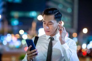 persona che gestisce volume su auricolare bluetooth connesso a smartphone