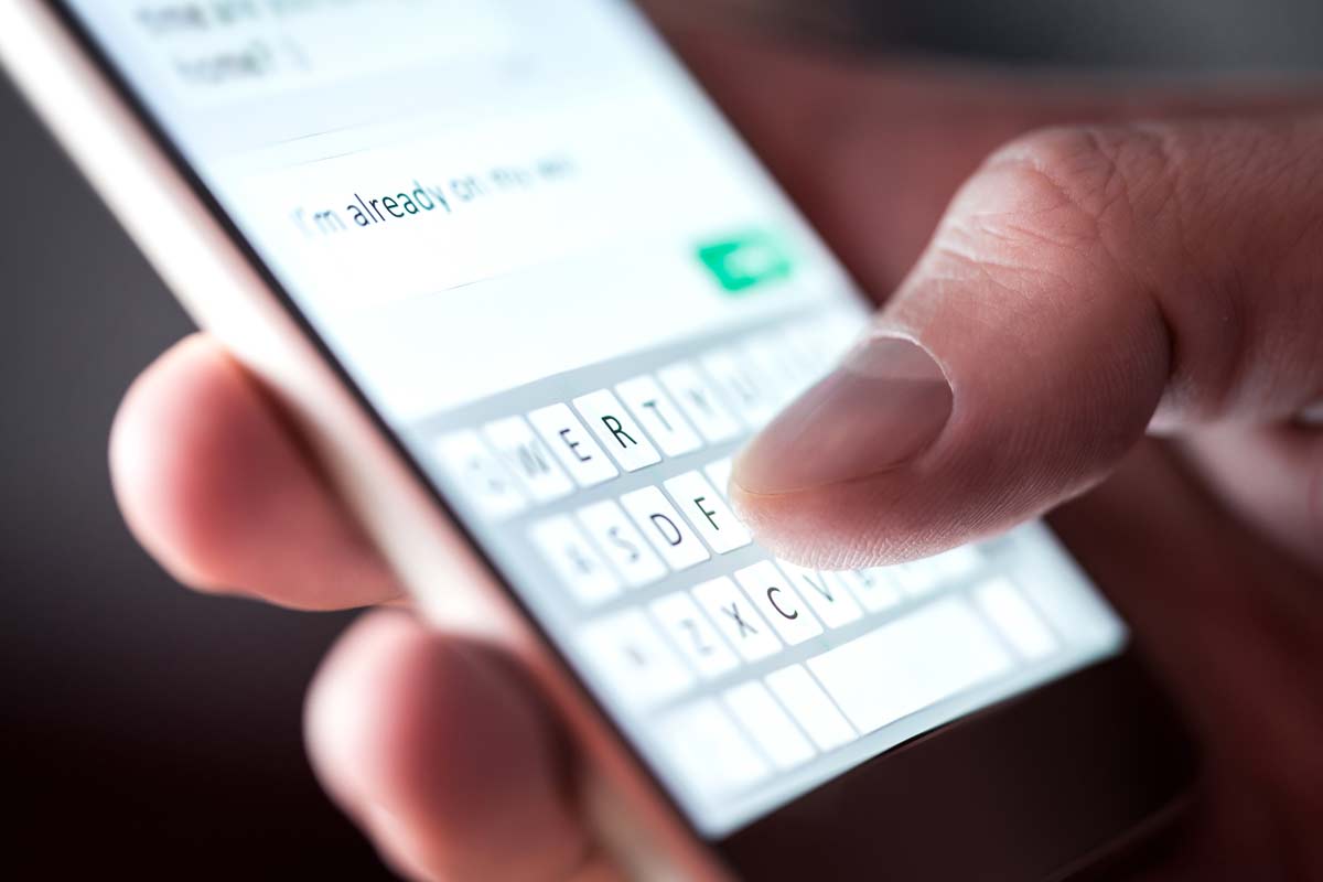 mano che scrive SMS con tastiera virtuale smartphone