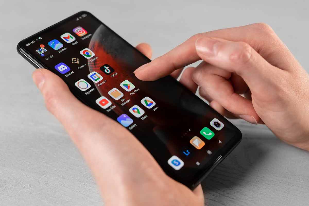 persona tiene in mano smartphone con icone app sullo schermo